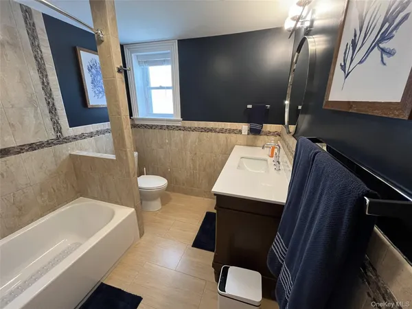 a bathroom with a sink a toilet a mirror and bathtub