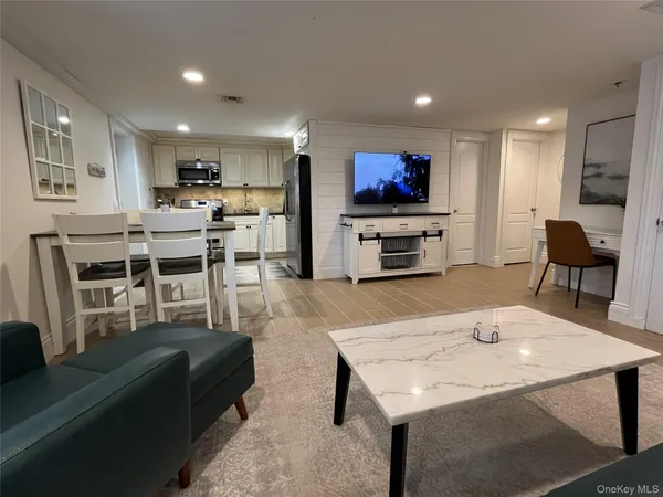 a living room with furniture a flat screen tv and kitchen view