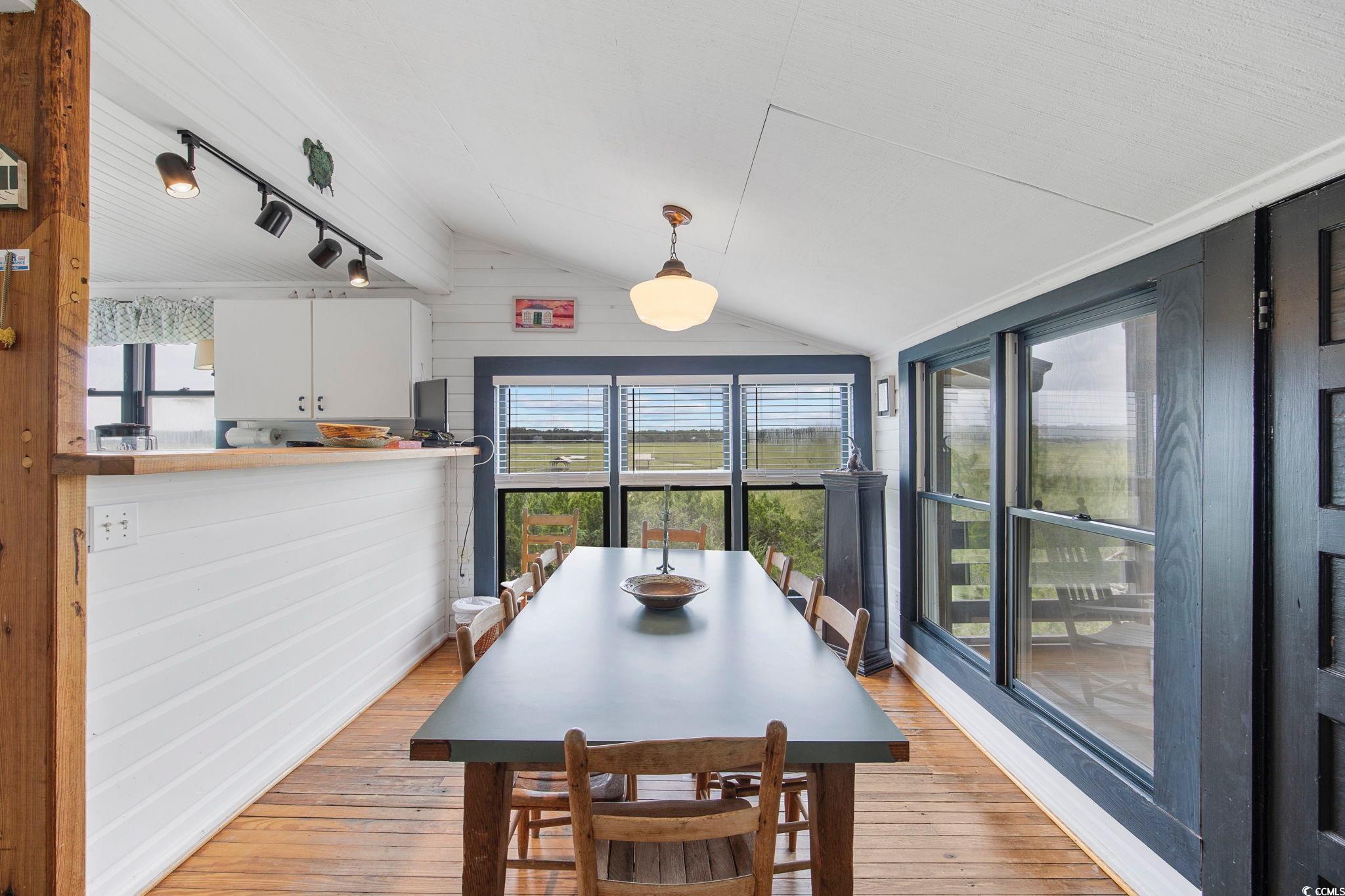 496 Myrtle Avenue Pawleys Island, SC 29585 - Photo 28 of 40 Dining room with light hardwood / wood-style floors, wooden walls, rail lighting, and vaulted ceiling