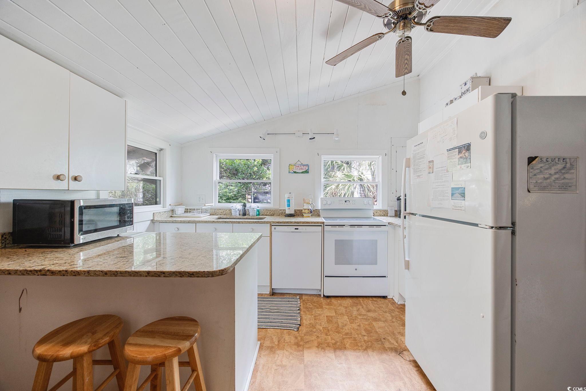496 Myrtle Avenue Pawleys Island, SC 29585 - Photo 10 of 40 Kitchen featuring white cabinetry, light hardwood / wood-style flooring, white appliances, kitchen peninsula, and light stone counters