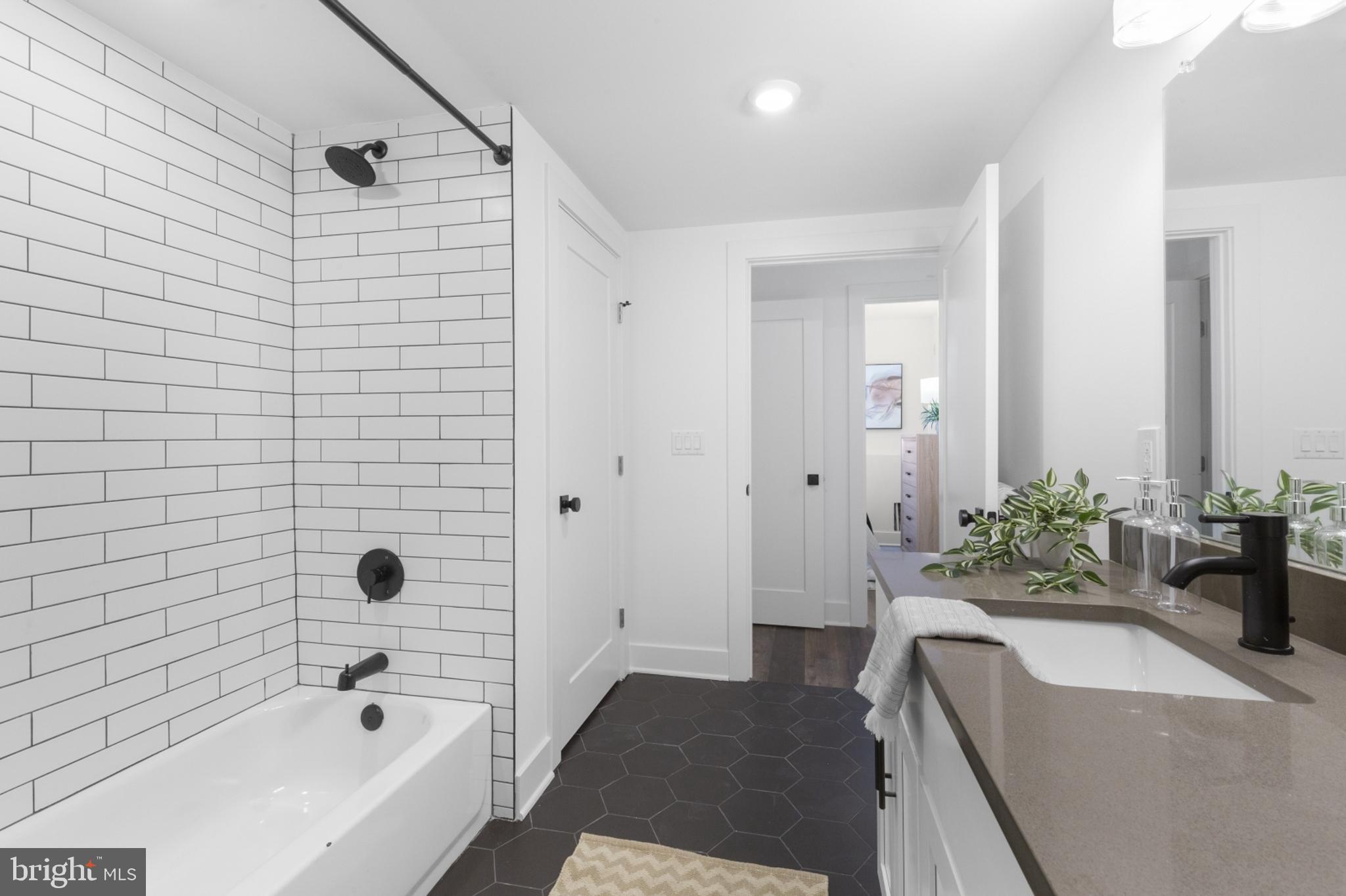 7037 Ridge Avenue, Unit 103 Philadelphia, PA 19128 - Photo 17 of 19 a bathroom with a granite countertop tub a sink and a large mirror