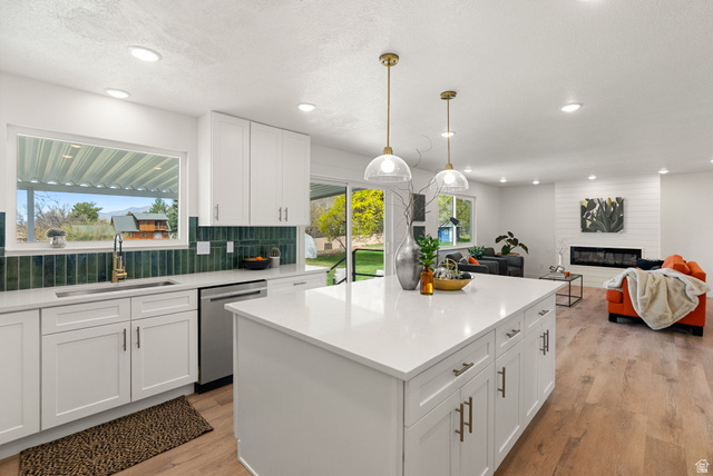 368 Spring Creek Road Providence, UT 84332 - Photo 45 of 45 Kitchen with white cabinets, a large fireplace, open floor plan, decorative backsplash, and a textured ceiling