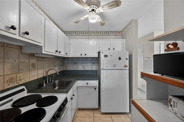 a living room with furniture a flat screen tv and a refrigerator