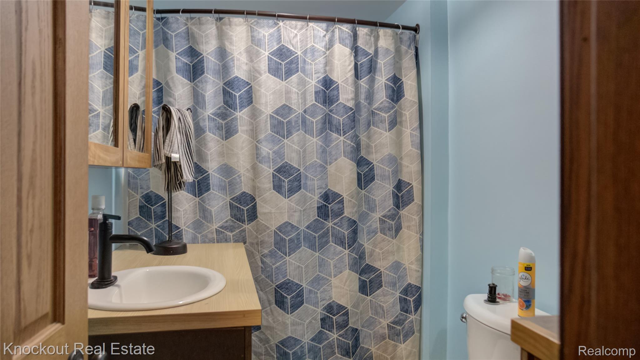 4195 Williamson Road Saginaw, MI 48601 - Photo 27 of 50 Bathroom featuring light blue walls, a light wood-finish vanity countertop, and dark cabinetry