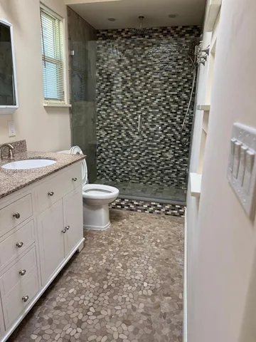 a bathroom with a granite countertop toilet and a sink