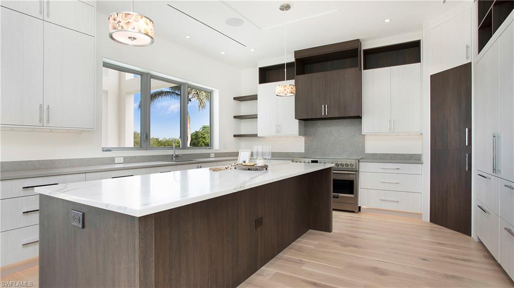 1798 Holiday Lane Naples, FL 34104 - Photo 12 of 47 Kitchen featuring open shelves, a center island, high end stainless steel range, light wood-type flooring, and decorative light fixtures