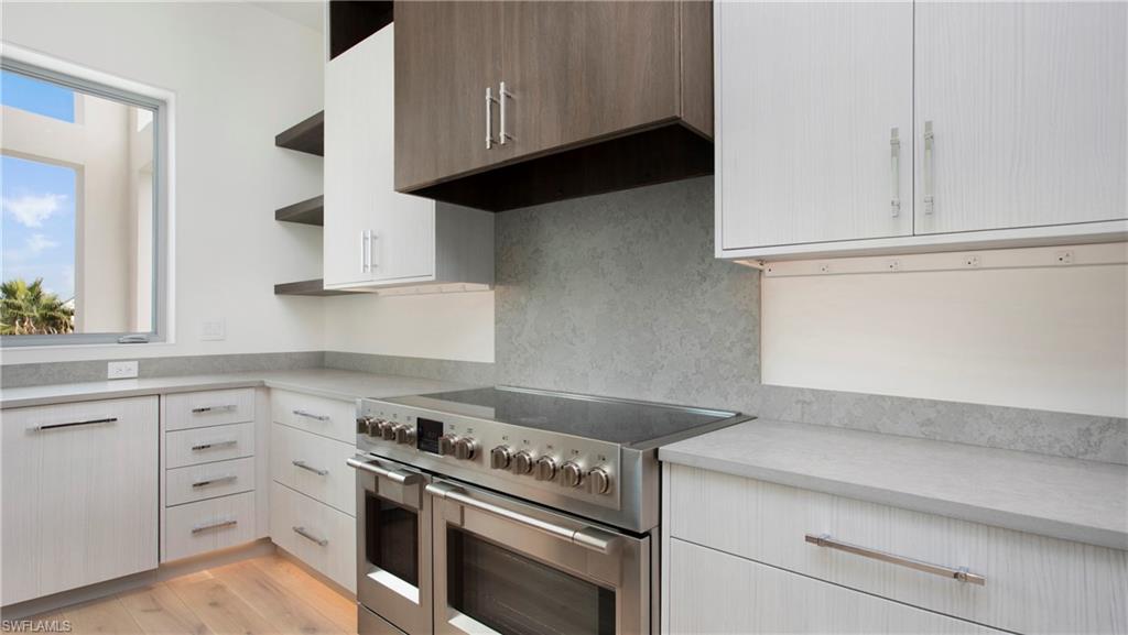 1798 Holiday Lane Naples, FL 34104 - Photo 13 of 47 Kitchen featuring open shelves, range with two ovens, light countertops, light wood-type flooring, and extractor fan