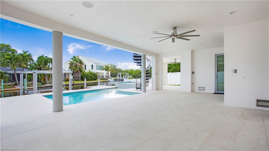 1798 Holiday Lane Naples, FL 34104 - Photo 38 of 47 View of pool with a ceiling fan, a pool with connected hot tub, a water view, and a patio