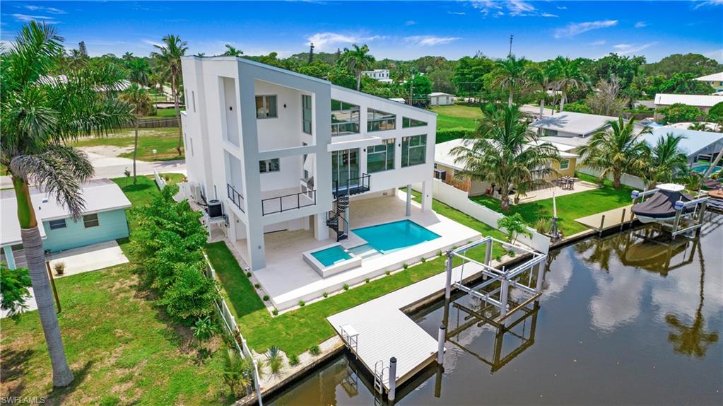 1798 Holiday Lane Naples, FL 34104 - Photo 45 of 47 Rear view of property featuring boat lift, a balcony, stucco siding, and a patio