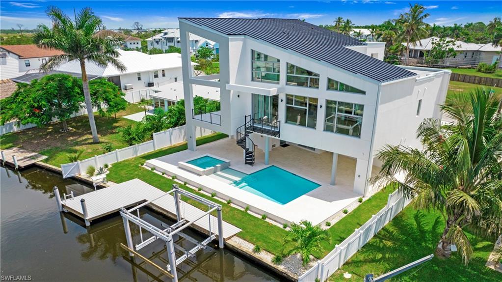 1798 Holiday Lane Naples, FL 34104 - Photo 46 of 47 Back of house featuring boat lift, a fenced backyard, a standing seam roof, and a patio