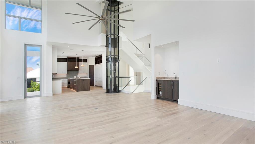 1798 Holiday Lane Naples, FL 34104 - Photo 9 of 47 Unfurnished living room with light wood-style flooring, stairs, and a towering ceiling