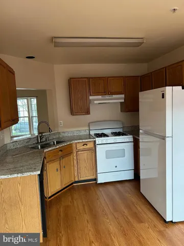 a kitchen with granite countertop a refrigerator sink stove and cabinets