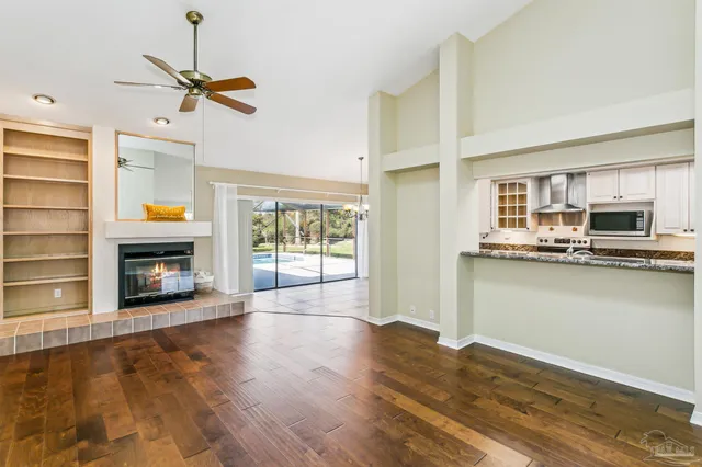 a view of a kitchen with furniture a ceiling fan and wooden floor