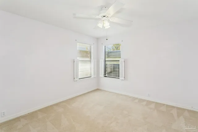 an empty room with windows and ceiling fan