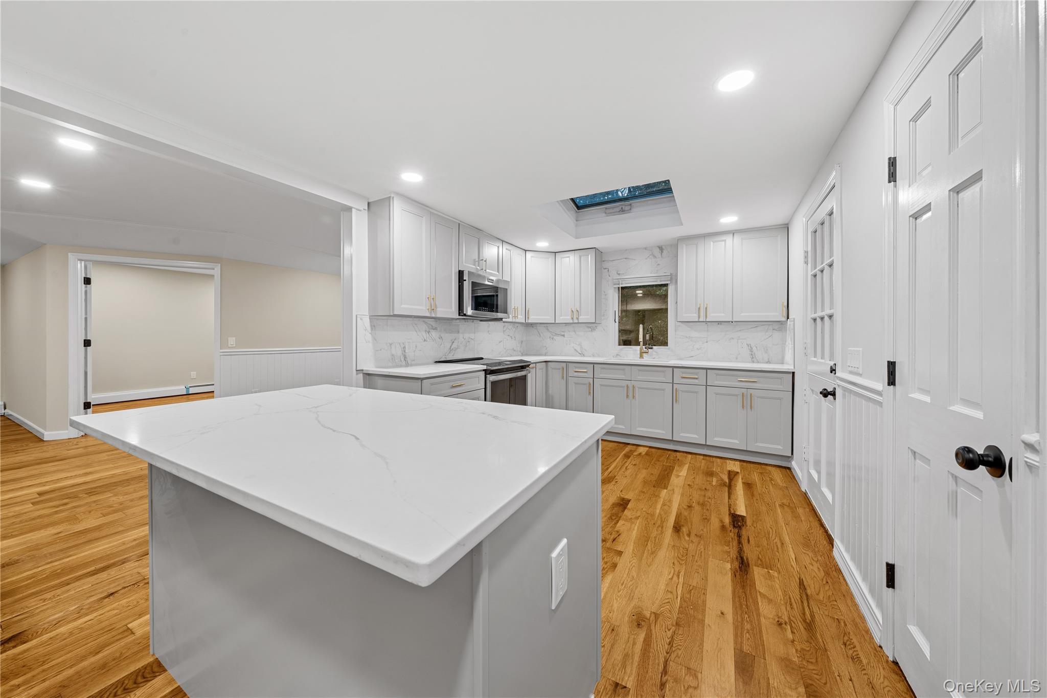57 Eastwood Road Miller Place, NY 11764 - Photo 13 of 49 a large white kitchen with wooden floor and a sink