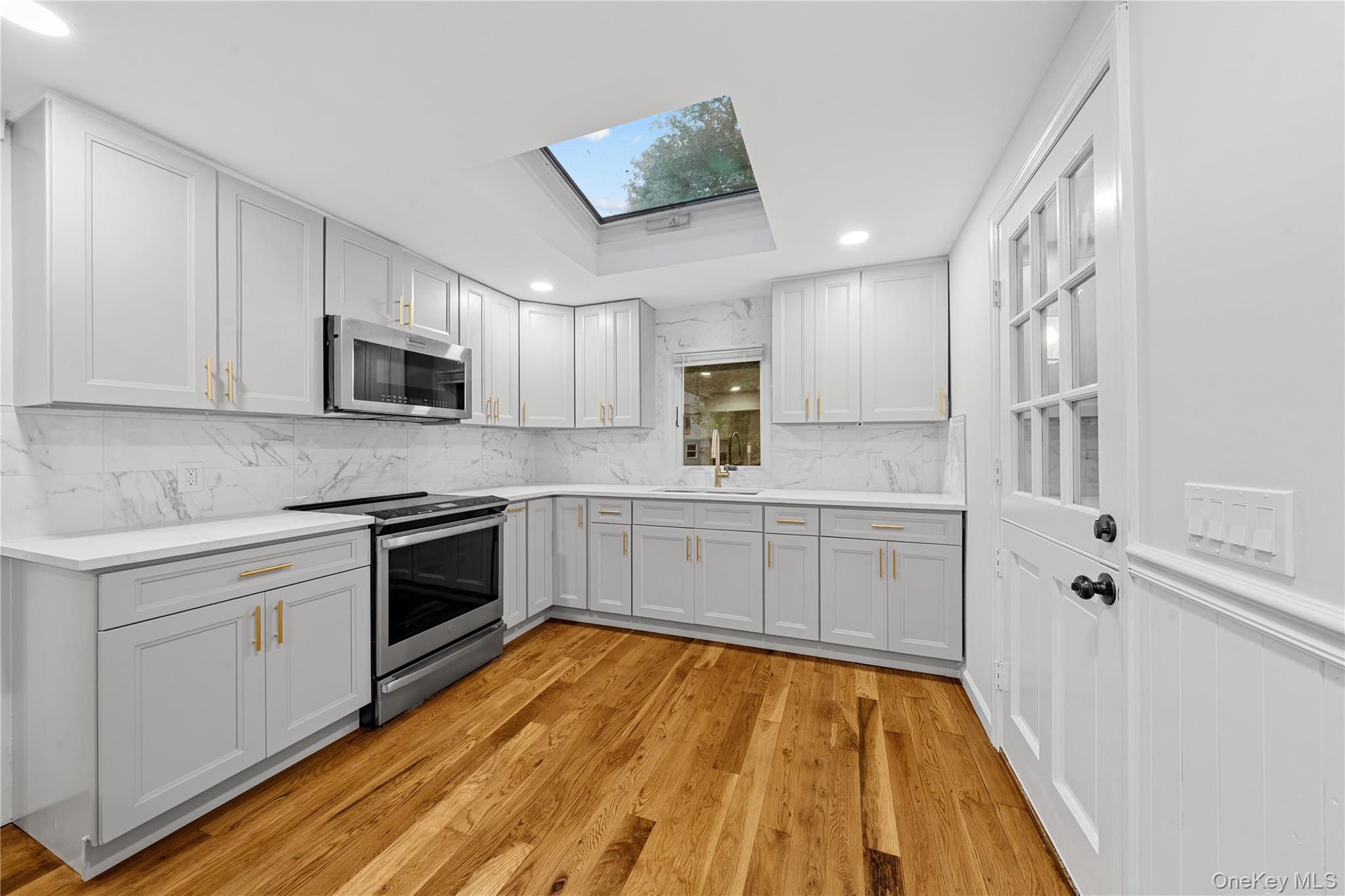 57 Eastwood Road Miller Place, NY 11764 - Photo 14 of 49 a kitchen with wooden floors and white appliances