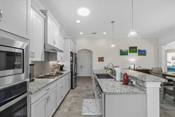 a large kitchen with granite countertop lots of counter space and stainless steel appliances