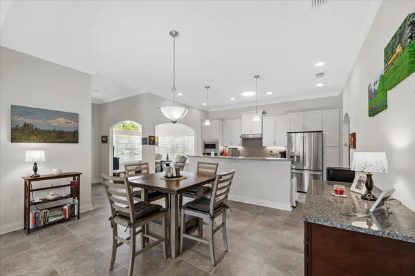 a view of a dining room and livingroom with furniture wooden floor a rug a flat screen tv a painting and a chandelier