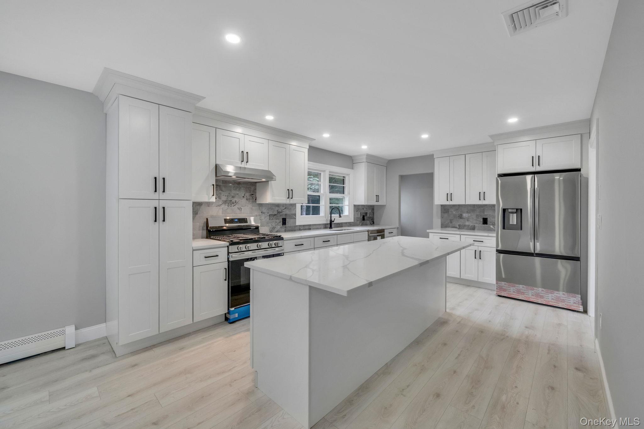 827 Aberdeen Road Bay Shore, NY 11706 - Photo 11 of 40 a kitchen with stainless steel appliances white cabinets a sink a stove a refrigerator and cabinets