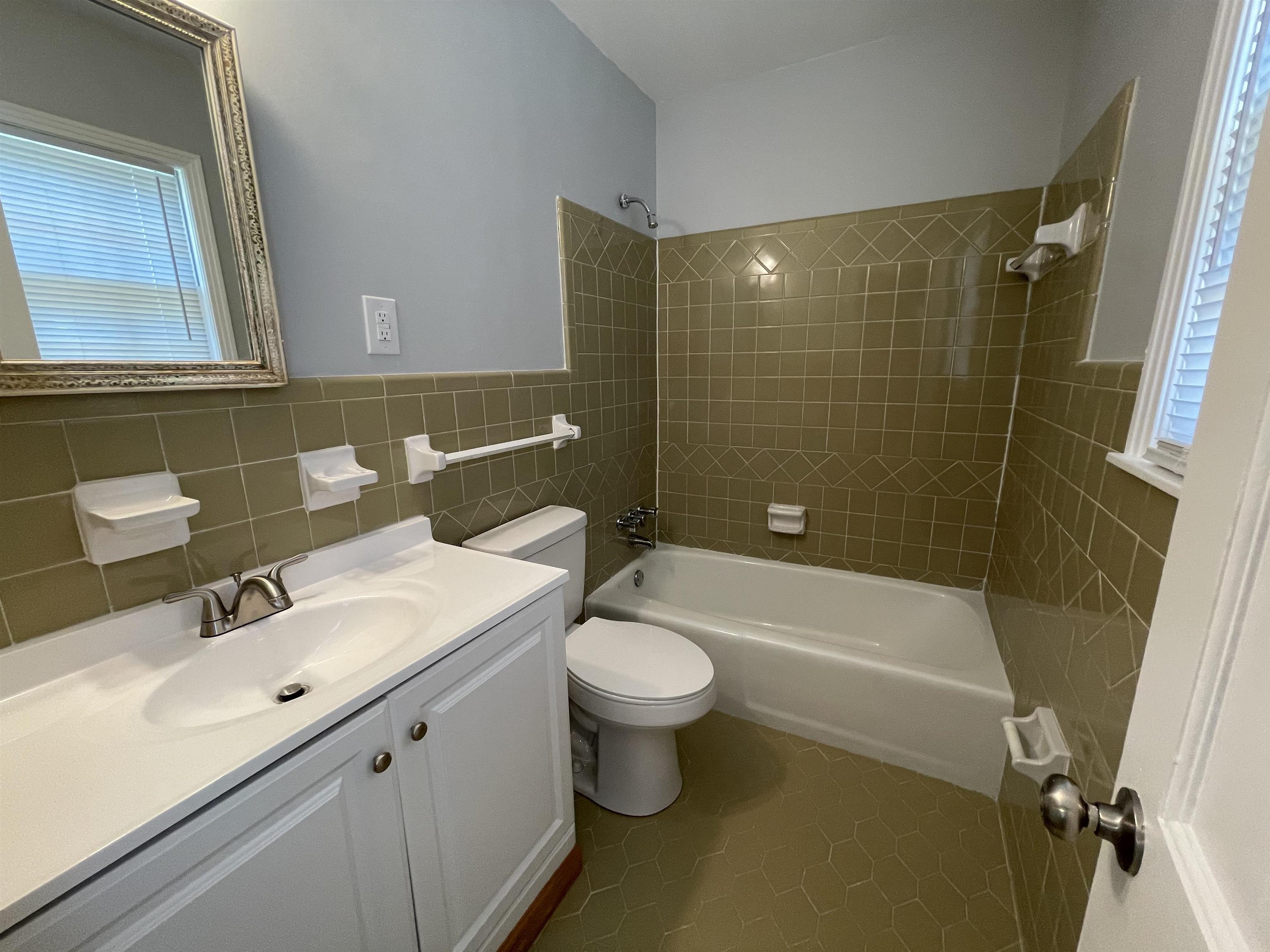379 McElroy Road Memphis, TN 38120 - Photo 17 of 22 Bathroom featuring a built-in tub with an integrated shower, green tile surround, and a white vanity with a single basin sink