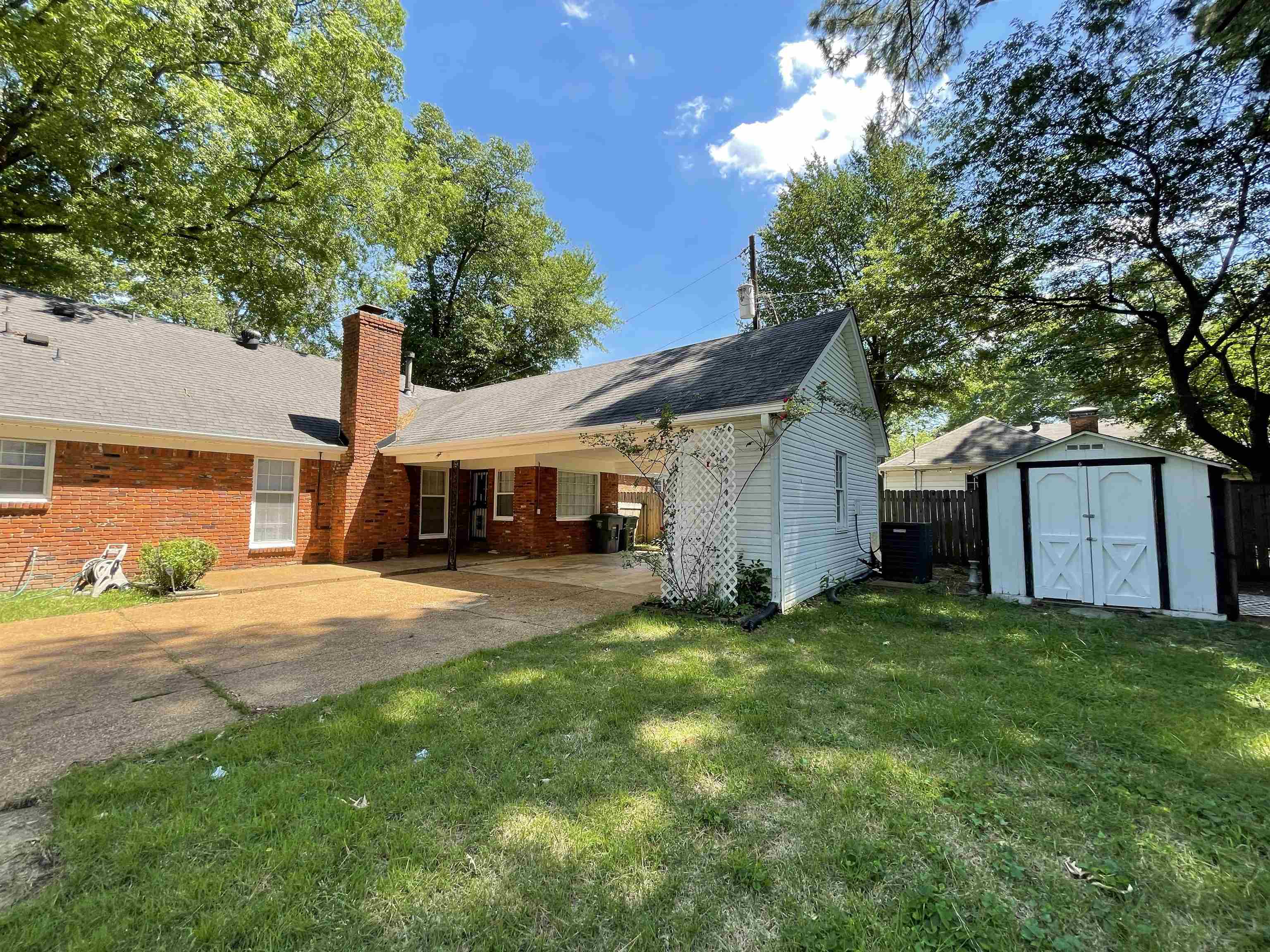 379 McElroy Road Memphis, TN 38120 - Photo 2 of 22 Rear exterior featuring a brick facade, covered patio area, and an expansive concrete pad
