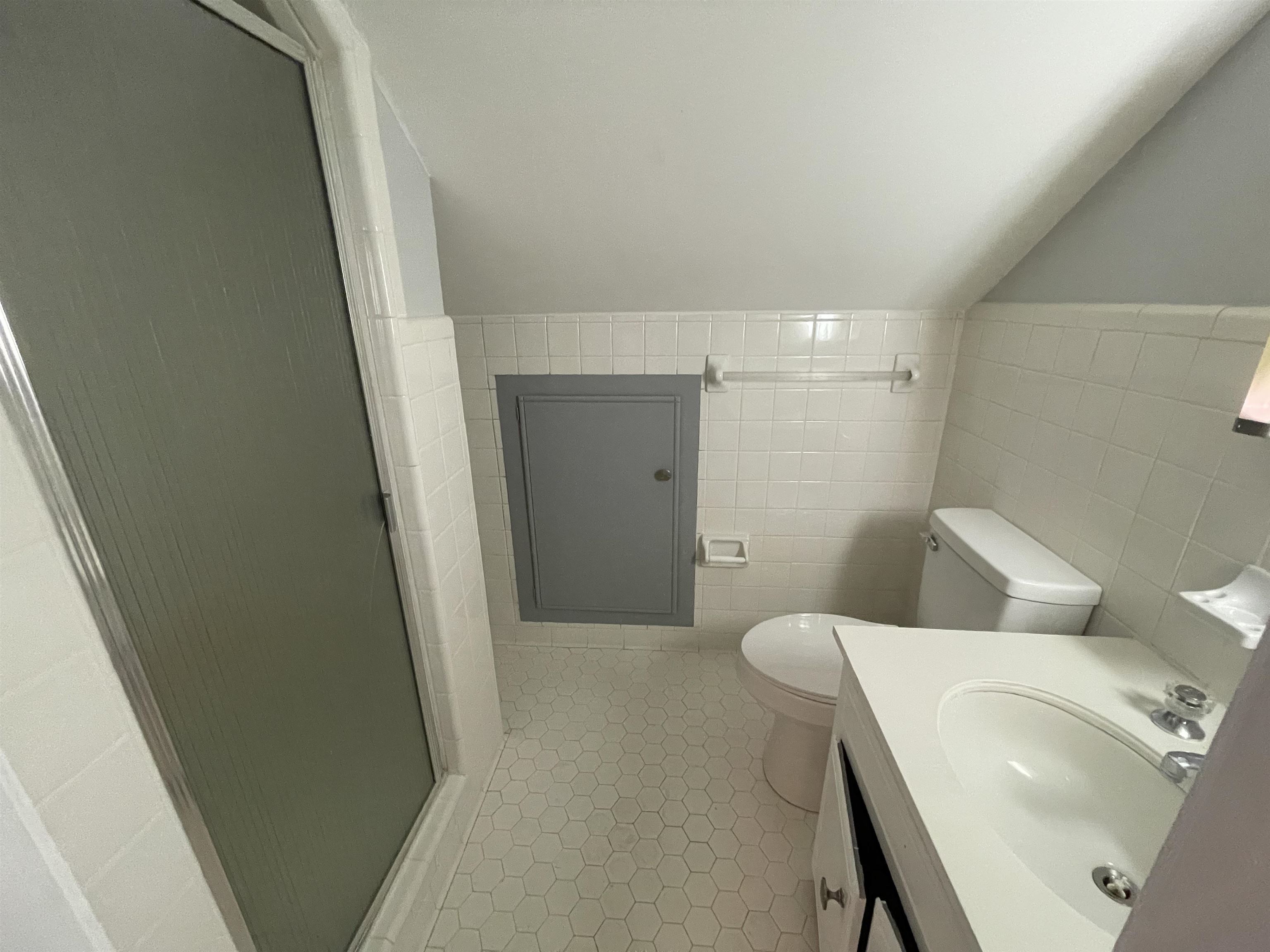 379 McElroy Road Memphis, TN 38120 - Photo 22 of 22 Bathroom featuring a glass-enclosed shower, hex tile flooring, white tile wainscoting, and a single-basin vanity with a white countertop