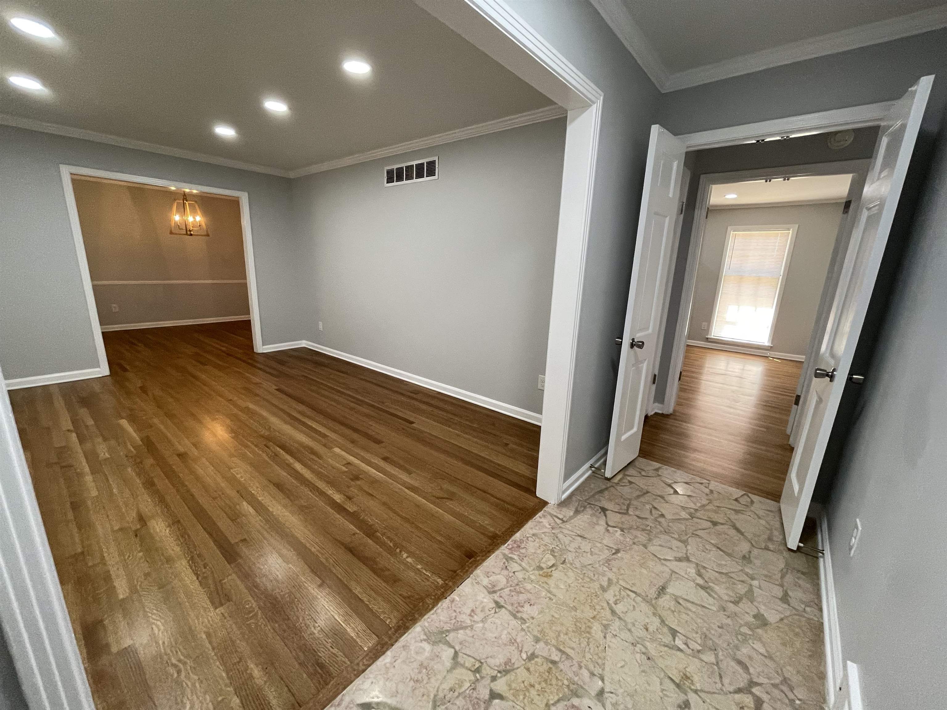 379 McElroy Road Memphis, TN 38120 - Photo 3 of 22 Entryway featuring natural stone-look flooring, leading to a room with wood-finish flooring, recessed lighting, and crown molding