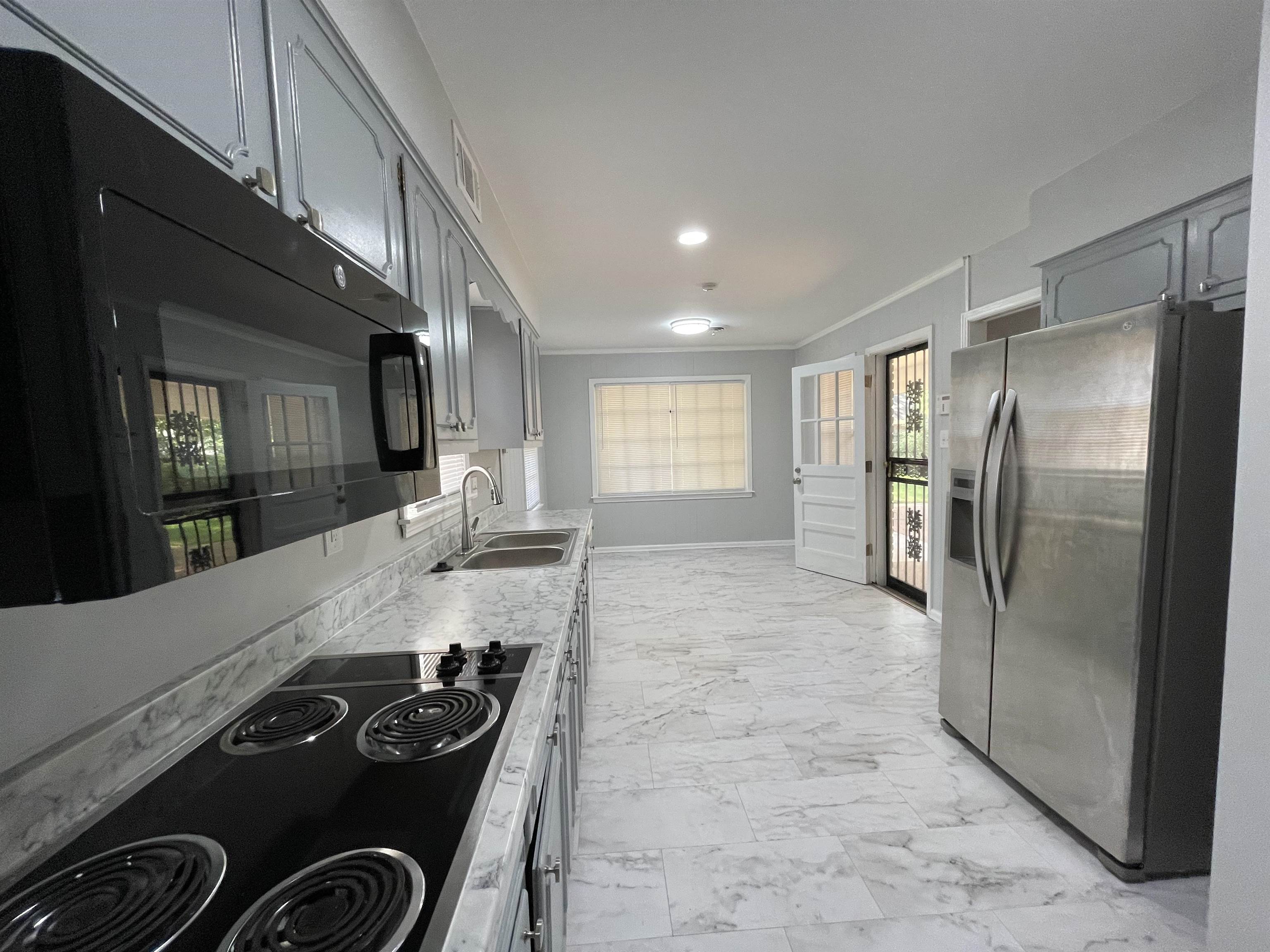 379 McElroy Road Memphis, TN 38120 - Photo 6 of 22 Kitchen featuring an electric cooktop, stainless steel appliances, dual basin sink, light-toned cabinetry, and patterned floor tiling