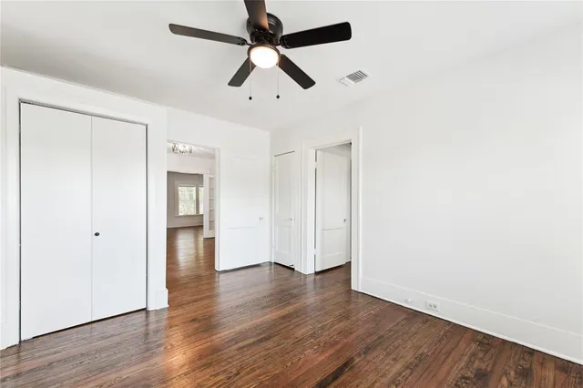 an empty room with wooden floor ceiling fan and window