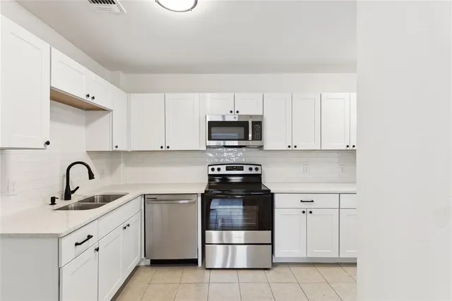 a kitchen with white cabinets and appliances