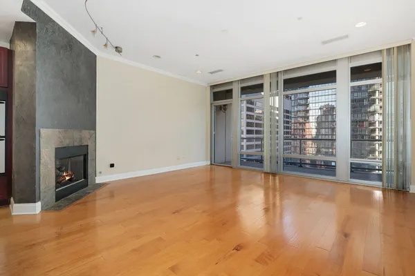 a view of an empty room with a fireplace and wooden floor