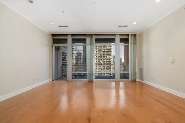 a view of an empty room with wooden floor and a window