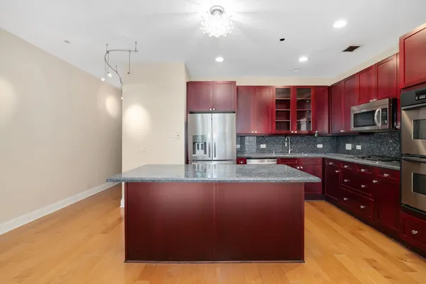 a large kitchen with stainless steel appliances granite countertop a stove a sink and a refrigerator