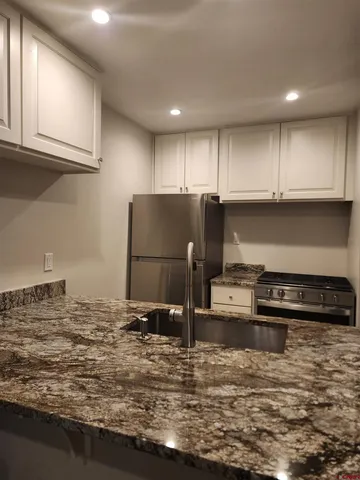 a kitchen with kitchen island granite countertop a refrigerator and a stove top oven
