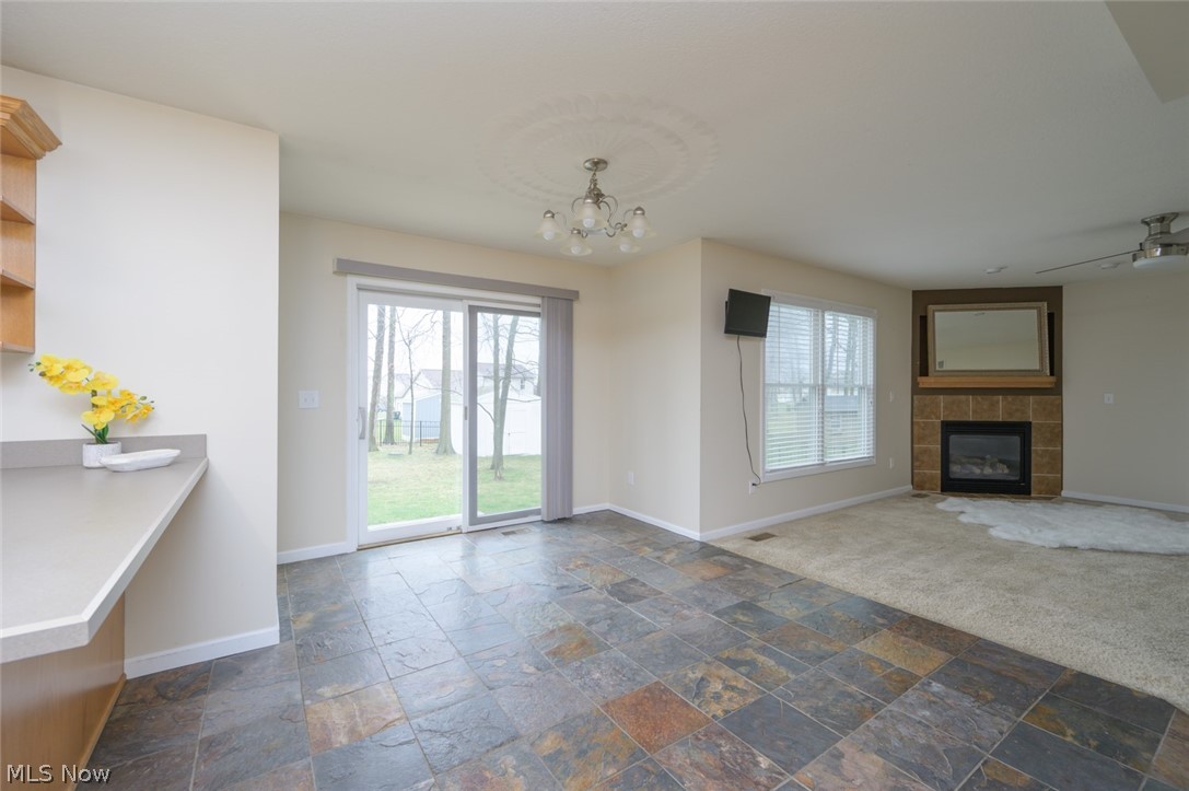 1060 Susan Road Ravenna, OH 44266 - Photo 7 of 25 open room with an inviting chandelier, a fireplace view , and dark slate flooring
