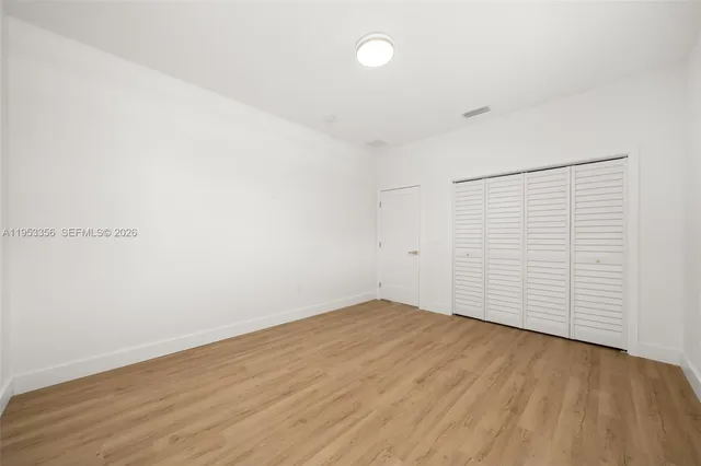 an empty room with wooden floor and white walls