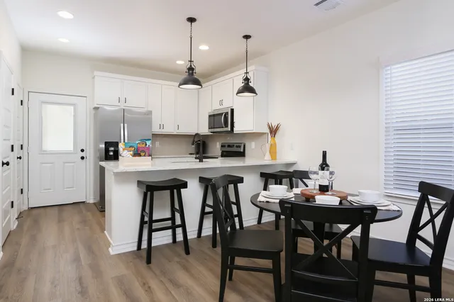 a kitchen with a dining table chairs and white cabinets
