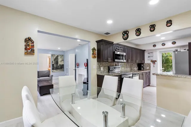 a living room with stainless steel appliances furniture a dining table and chairs