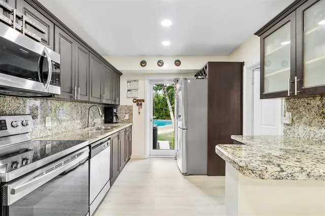 a kitchen with stainless steel appliances granite countertop a refrigerator a stove and a sink