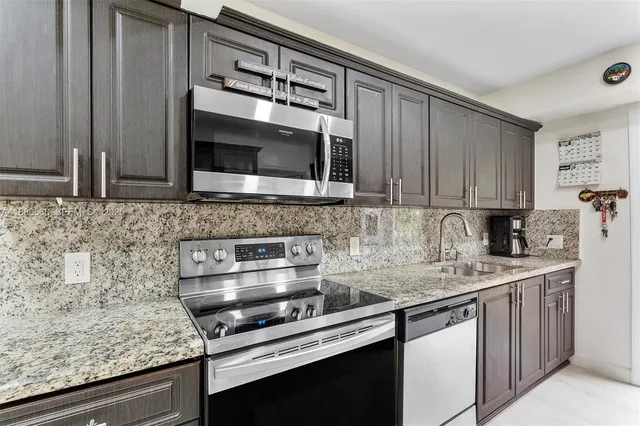 a kitchen with stainless steel appliances granite countertop a sink and a microwave