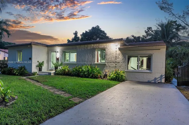 a view of a house with brick walls and a yard with plants