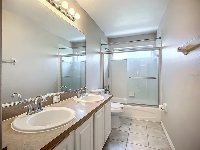 a bathroom with a granite countertop sink a toilet a mirror and shower
