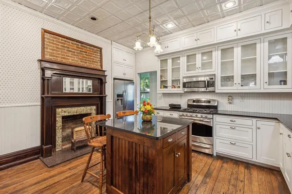 a kitchen with stainless steel appliances granite countertop a stove a refrigerator a kitchen island a stove and a wooden floors