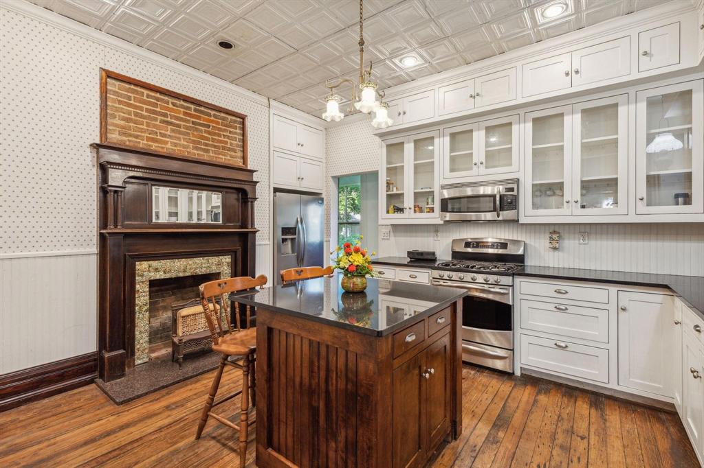 405 West Clifton Street Pilot Point, TX 76258 - Photo 4 of 33 a kitchen with stainless steel appliances granite countertop a stove a refrigerator a kitchen island a stove and a wooden floors