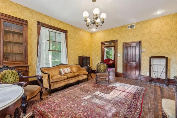 a living room with furniture a chandelier and wooden floor
