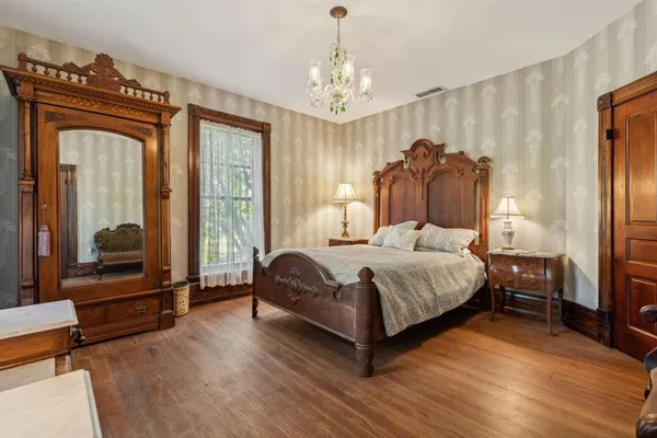 a bedroom with a bed couch and a large window with wooden floor