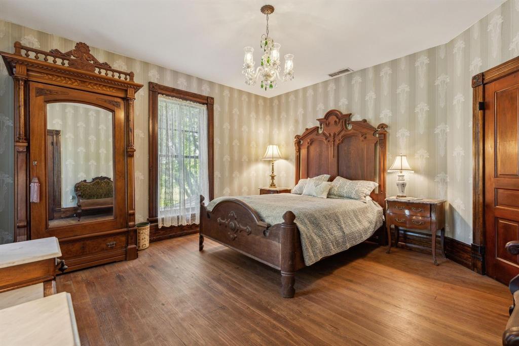 405 West Clifton Street Pilot Point, TX 76258 - Photo 10 of 33 a bedroom with a bed couch and a large window with wooden floor