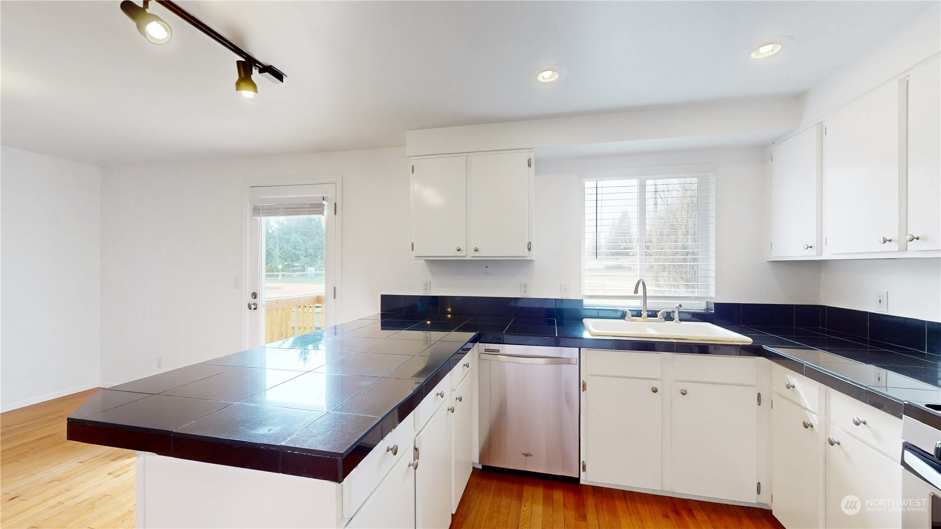 6426 Cady Road Everett, WA 98203 - Photo 28 of 39 a kitchen with a sink dishwasher and white cabinets with wooden floor