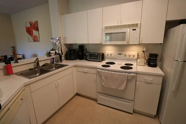a kitchen with white cabinets and white appliances
