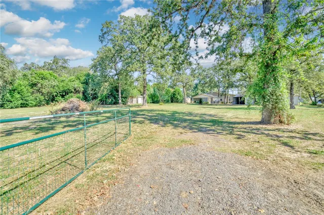 a view of a house with a big yard and large trees